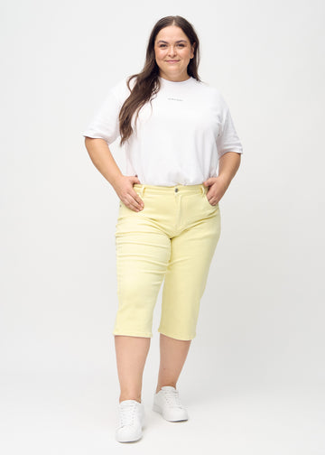 Lysegule regular capris set bagfra tæt på en plus-size model for at vise detaljer.
