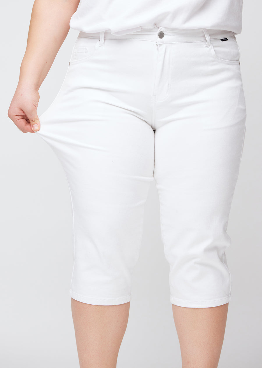 Plus-size model viser stretch ved at trække i caprisene ved låret – fokus på komfort og fleksibilitet.