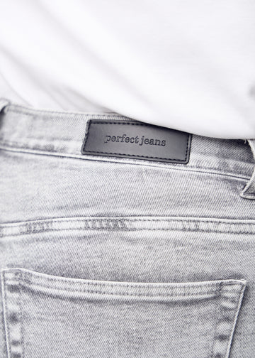 Nærbillede af lysegrå denim med Perfect Jeans læderpatch bagpå i taljen, på en plus-size model.