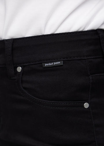Nærbillede af sort jeansmateriale med Perfect Jeans logoetiket ved forlommekanten.
