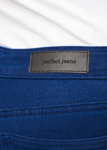 Nærbillede af mørkeblåt jeansmateriale med Perfect Jeans læderpatch bagpå i taljen, på en plus-size model.