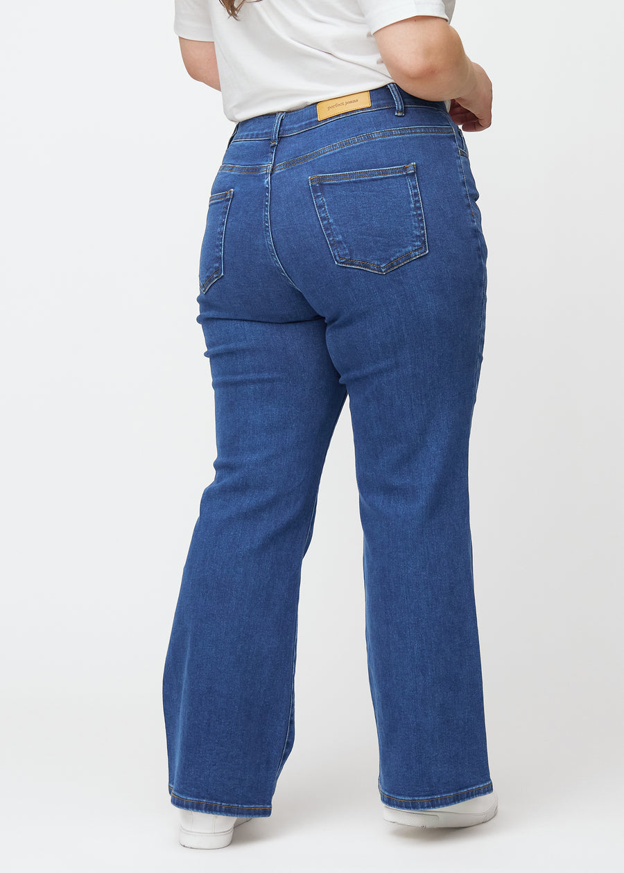 Dark blue mid-rise bootcut jeans in Oceans. Back view on a plus-size model, showing the full fit.
