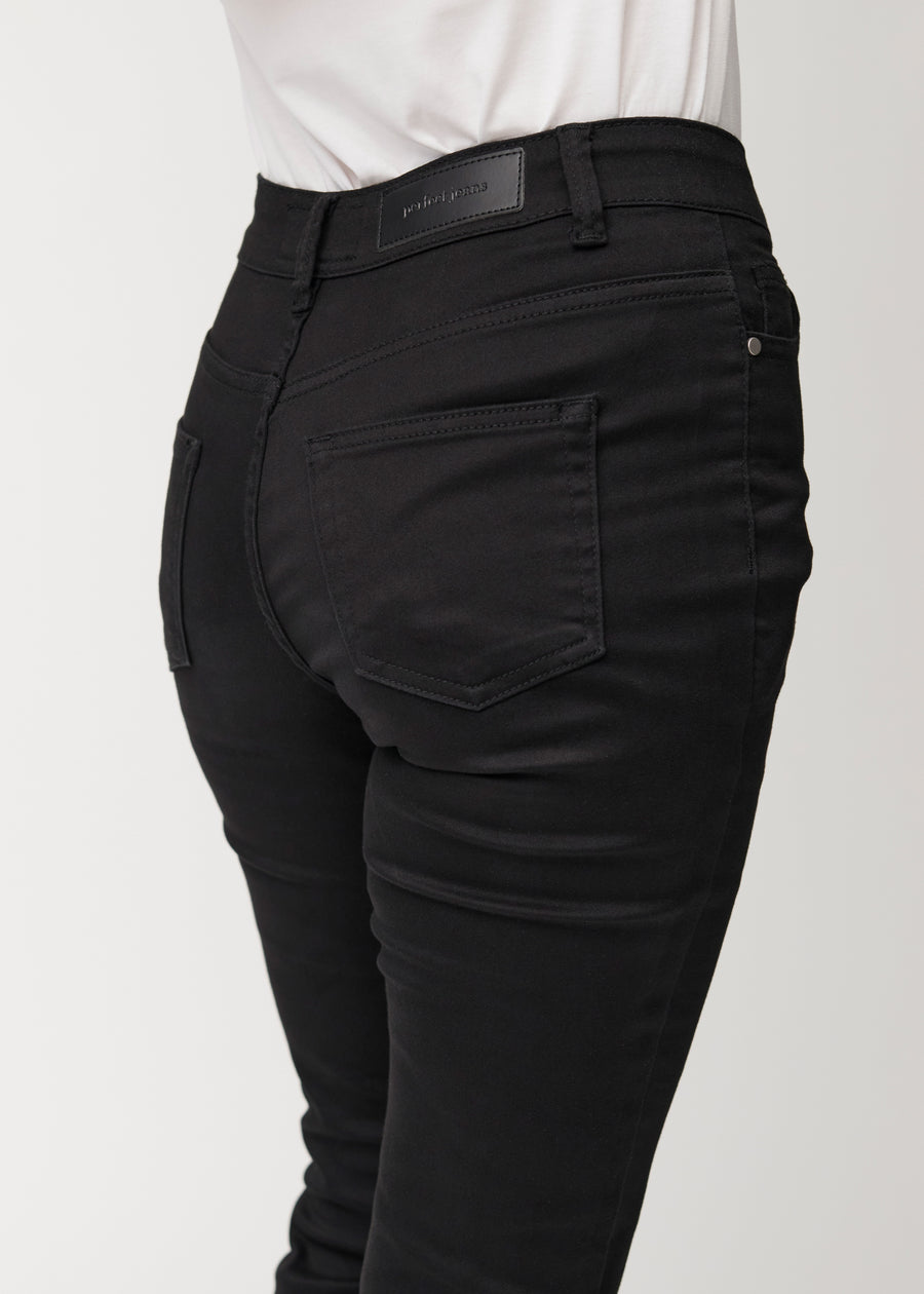 Black mid-rise bootcut jeans in Ravens. Close-up back view on a model, showing the details.
