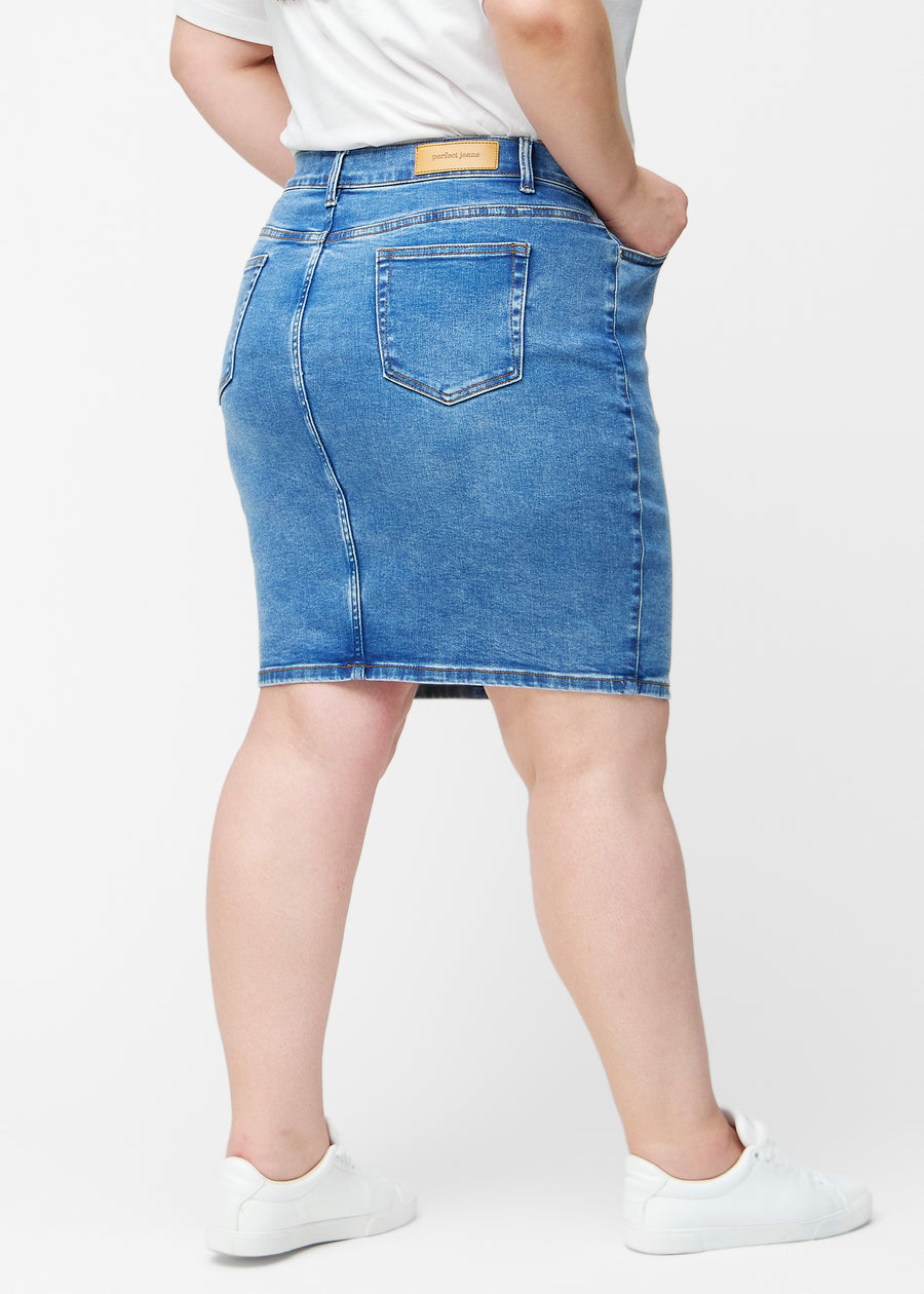 Klassisk blå, tætsiddende og knælang denimnederdel set bagfra på plus-size model, så hele produktet kan ses.