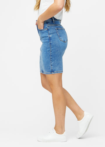 Klassisk blå, tætsiddende og knælang denimnederdel set fra siden på model.