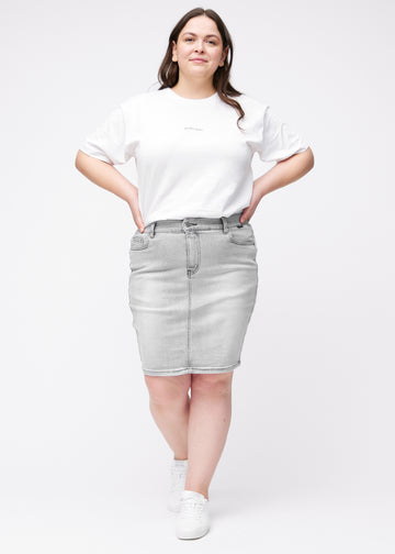 Fuldt billede af plus-size model i lysegrå, tætsiddende og knælang denimnederdel.