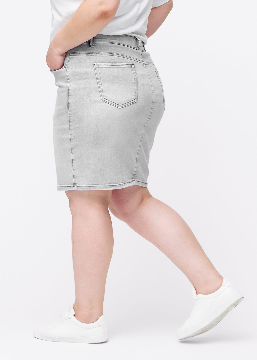 Lysegrå, tætsiddende og knælang denimnederdel set fra siden på plus-size model.