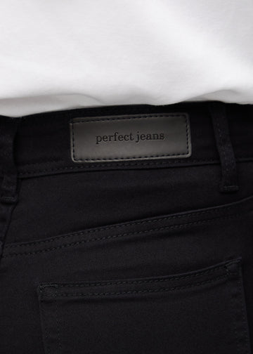 Nærbillede af sort jeansmateriale med Perfect Jeans læderpatch bagpå i taljen.
