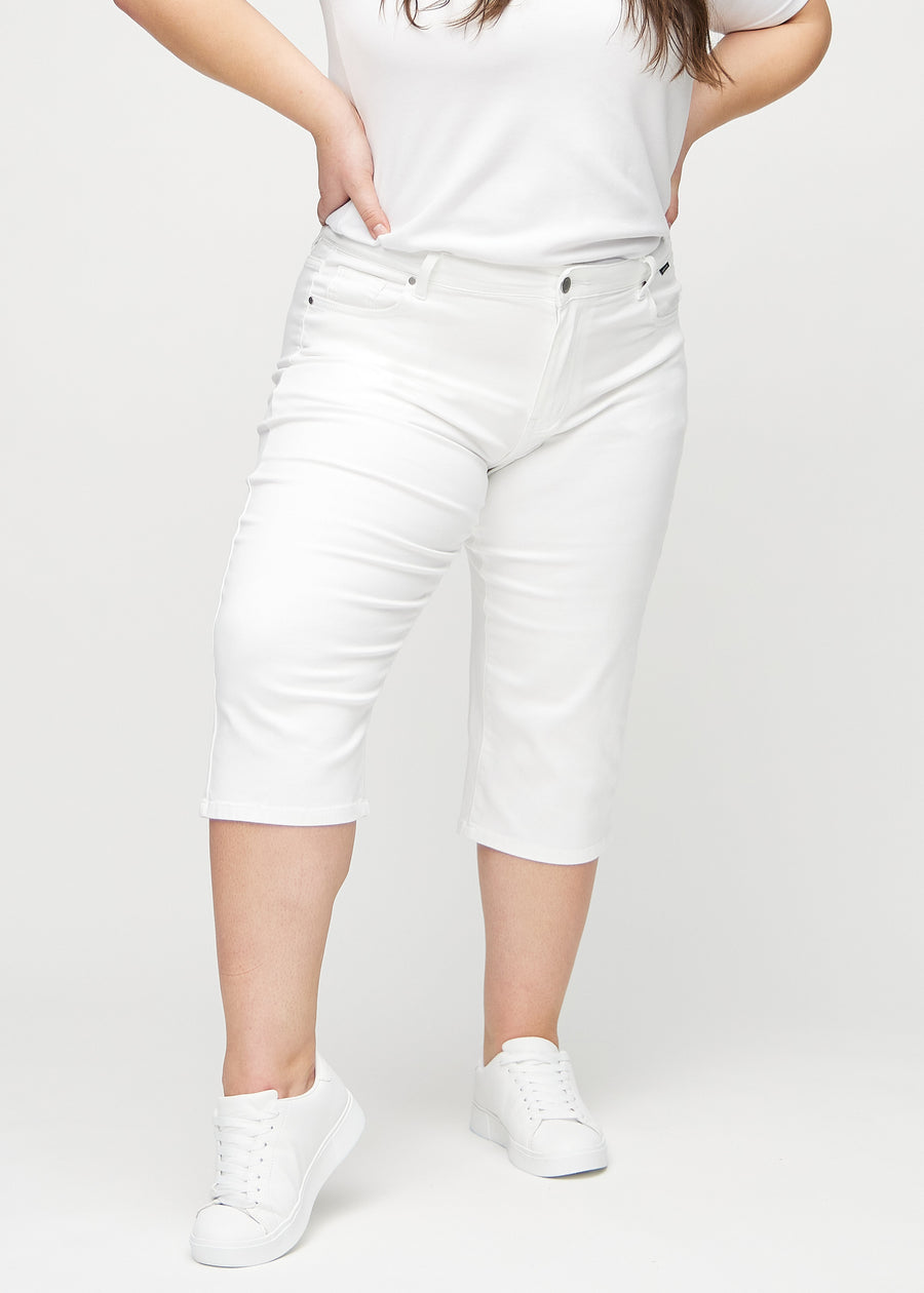 White regular capris, model name Marguerites, which have a straight fit through the leg and end just below the knee on a plus-size model, seen from the front.