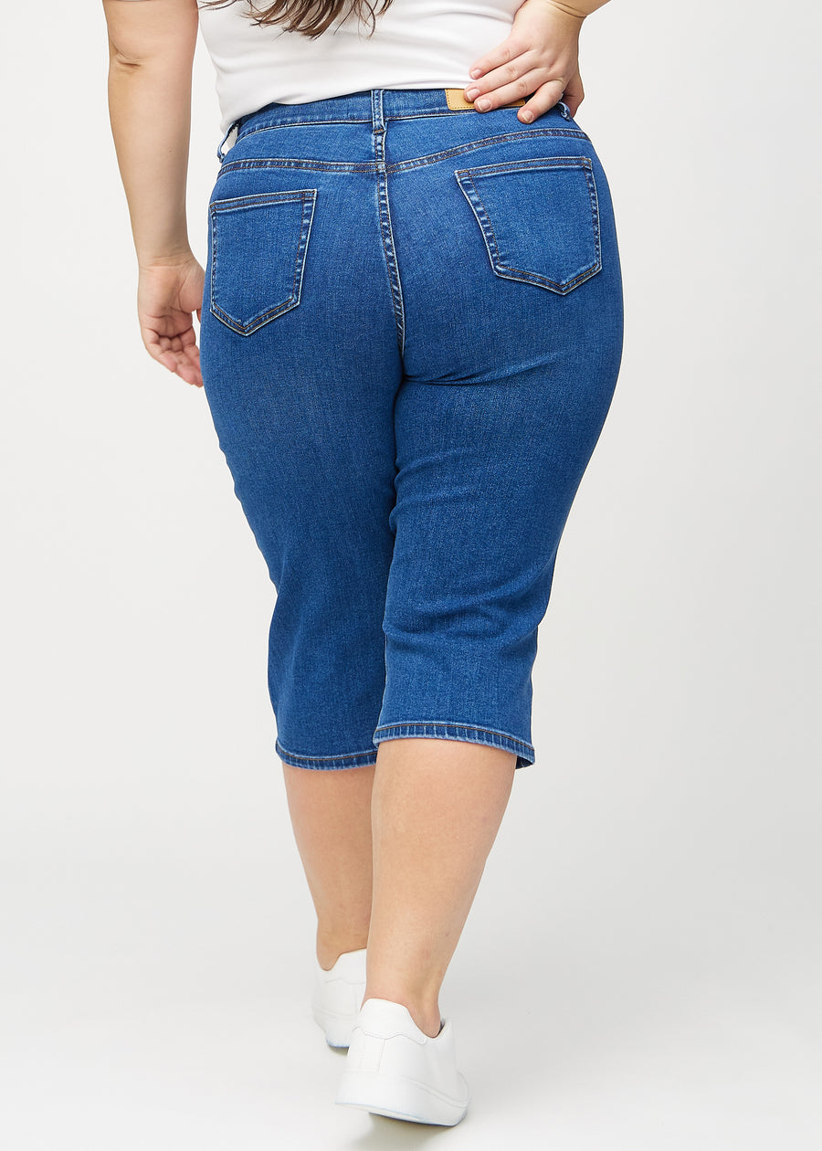 Dark denim regular capris seen from the back on a plus-size model, so you can see the entire product.