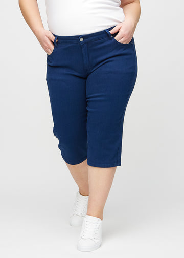 Dark blue regular capris, model name Royals, with a straight fit through the leg and ending just below the knee on a plus-size model, seen from the front.