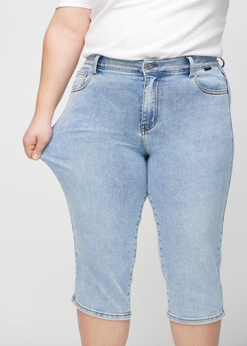 The plus-size model stretches the capris at the thigh to show the stretch.
