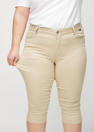 Skinny capris for women in beige fabric, color Gazelles. A plus-size model stretches the fabric to demonstrate its flexibility.