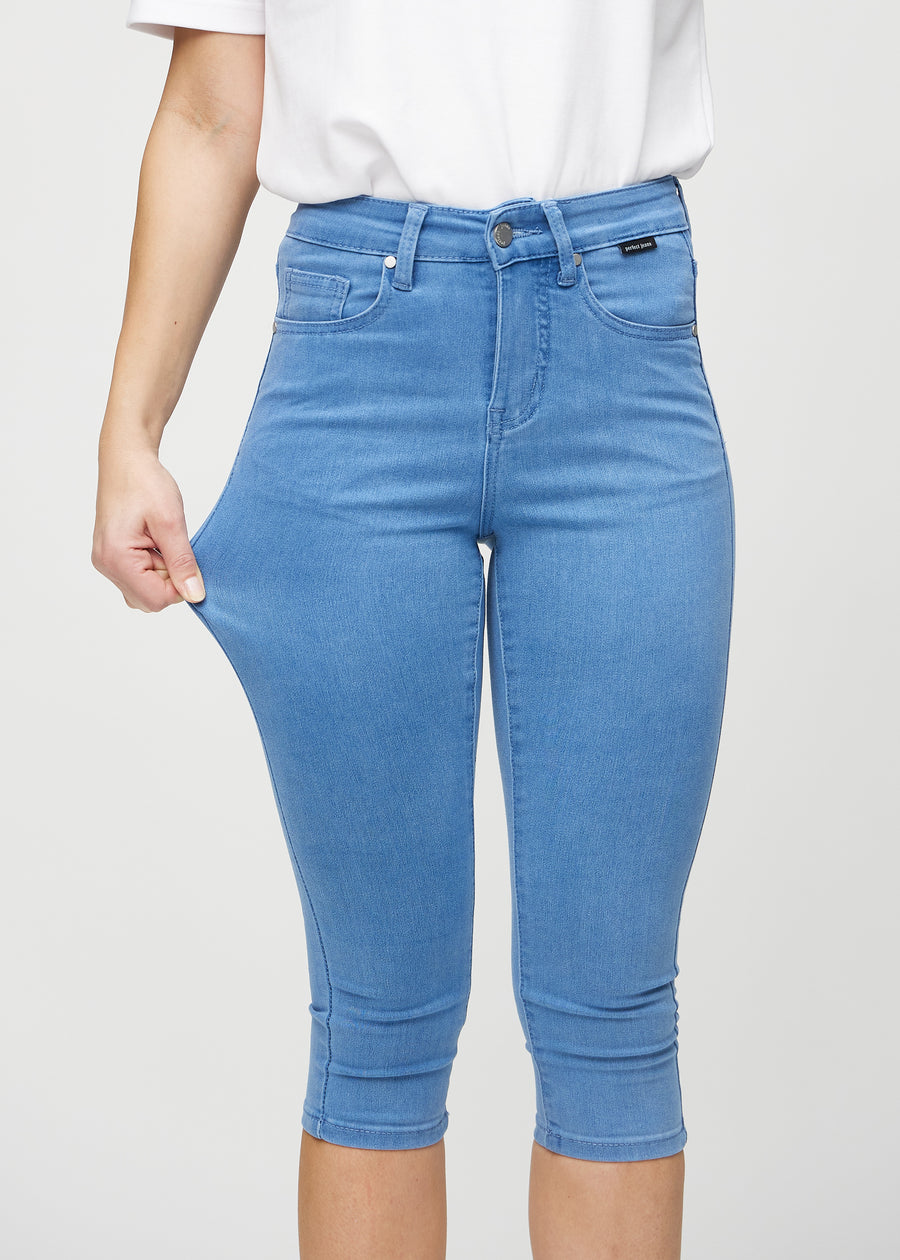 Skinny capris for women in blue fabric, color Geraniums. A model stretches the fabric to demonstrate its flexibility.