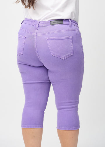 Skinny capris for women in pastel purple fabric, color Lavenders. Close-up from behind on a plus-size model, highlighting pockets and stitching.