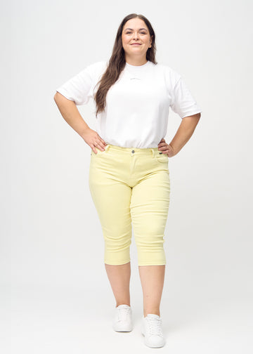 Full image of a plus-size model in light yellow skinny capris.