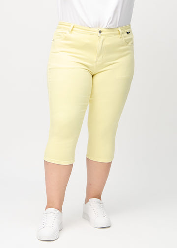 Light yellow skinny capris, model name Lemonades, fitted close to the leg on a plus-size model, front view.