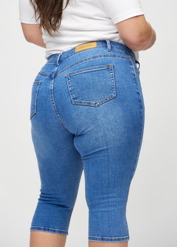 Denim skinny capris seen from the back close up on a plus-size model to show details.
