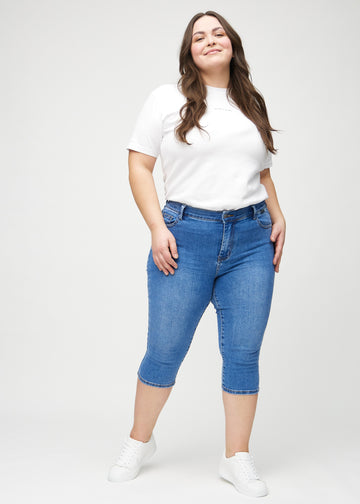 Full image of a plus-size model wearing denim skinny capris.