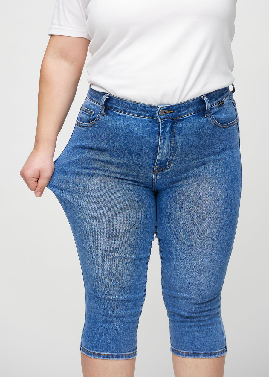 The plus-size model stretches the capris at the thigh to show the stretch.