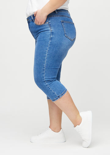 Denim skinny capris seen from the side on a plus-size model.