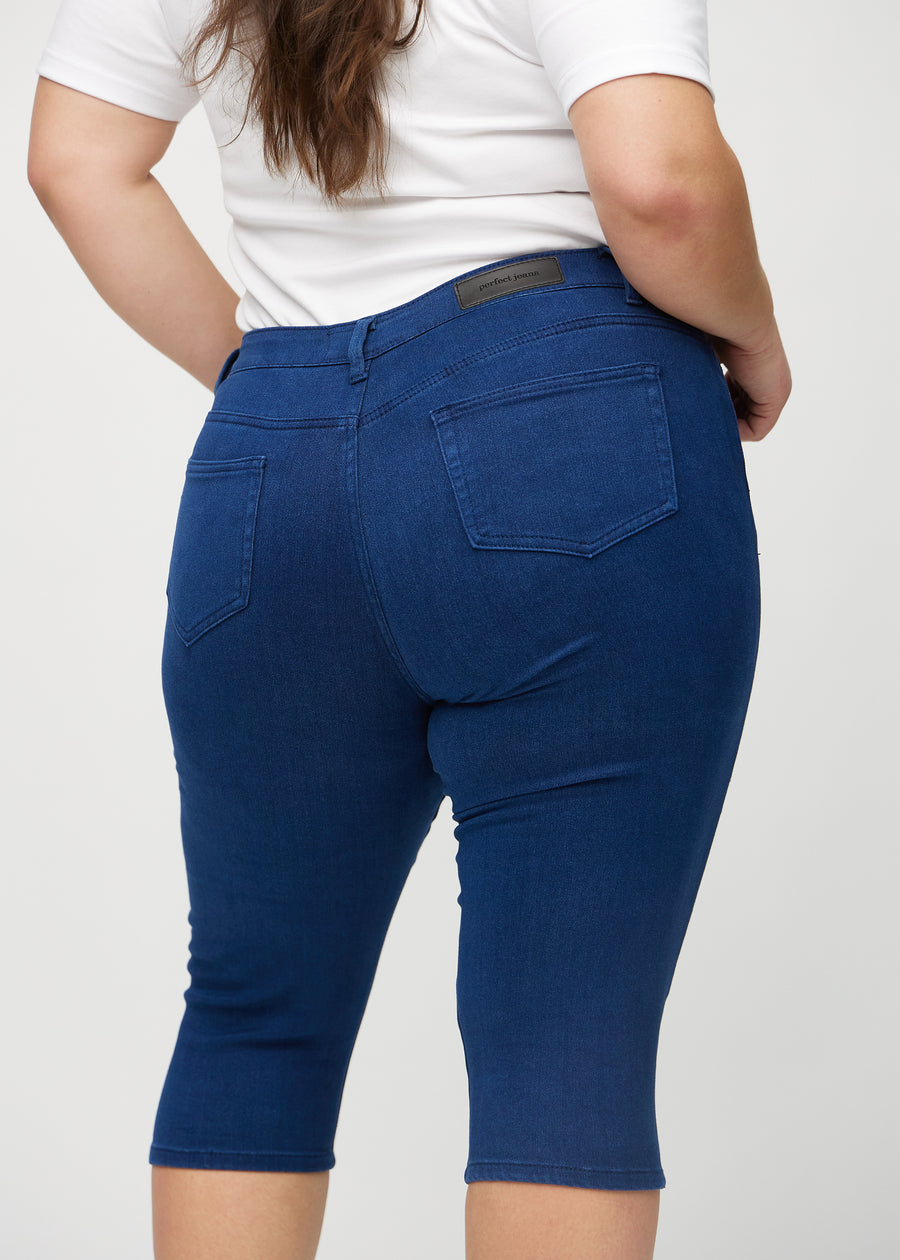Skinny capris for women in dark blue fabric, color Royals. Close-up from behind on a plus-size model, highlighting pockets and stitching.