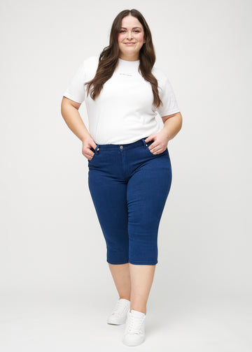 Skinny capris for women in dark blue fabric, color Royals. Full-length view of a plus-size model wearing the capris.
