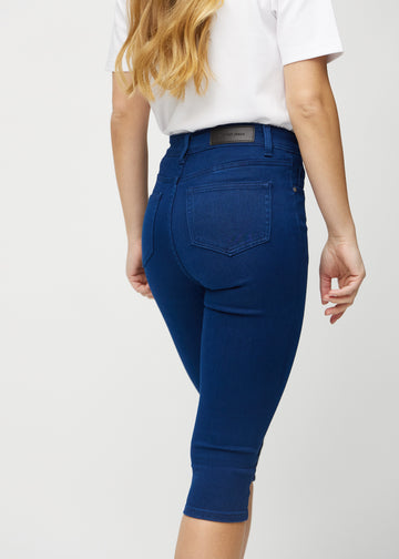 Skinny capris for women in dark blue fabric, color Royals. Close-up from behind on a model, highlighting pockets and stitching.