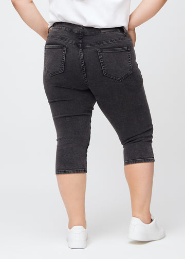Skinny capris for women in dark grey denim, color Shadows. Back view on a plus-size model, showing the fit and back pockets.