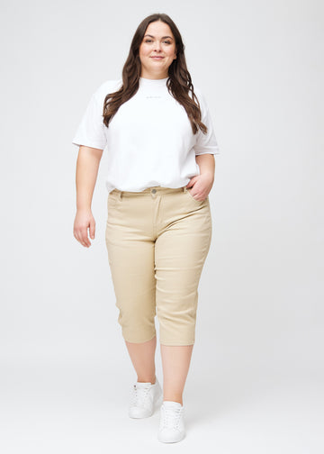  Full image of plus-size model in beige slim capris.