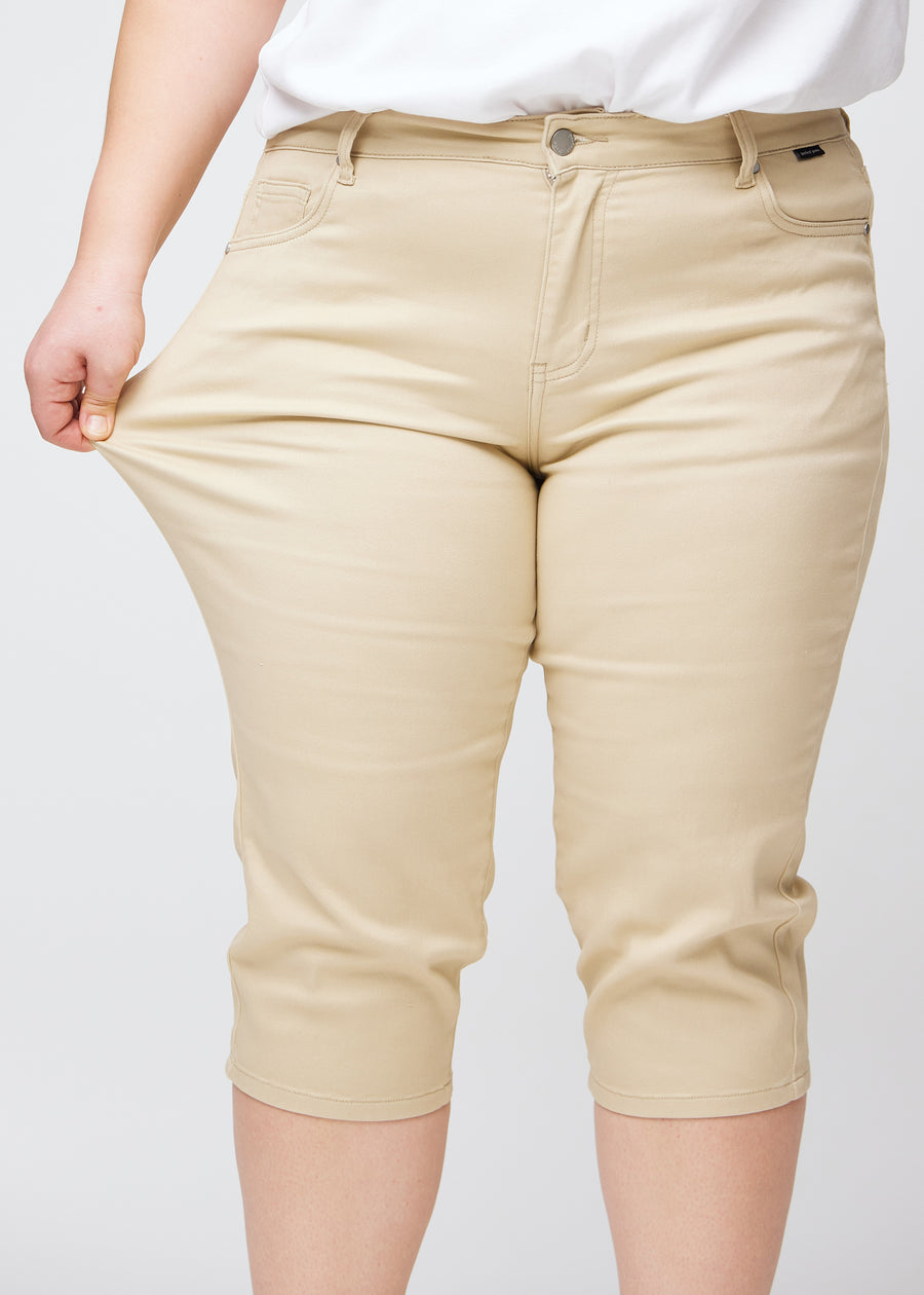  Plus-size model shows the stretch by pulling the capris at the thigh, focus on comfort and flexibility.