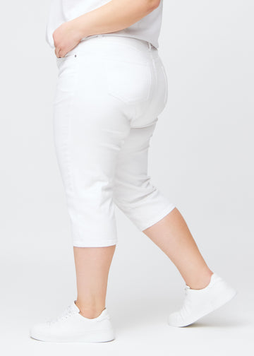 Slim capris for women in white jeans fabric, color Marguerites. Side view on a plus-size model, showing the tailored fit and mid-rise waist.