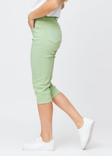 Slim capris for women in pastel light green jeans fabric, color Mints. Side view on a model, showing the tailored fit and mid-rise waist.