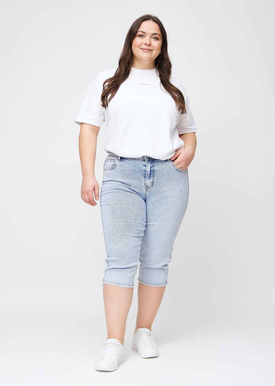 Full image of plus-size model in light blue denim slim capris.