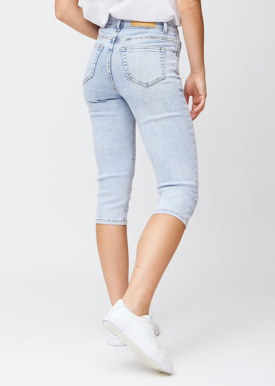 Light blue denim slim capris seen from the back, the entire product is shown on the model with focus on fit and length.