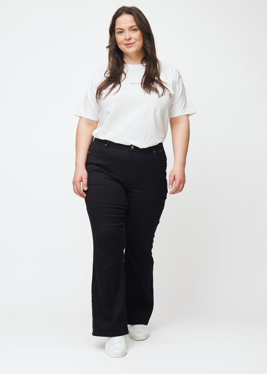 Black mid-rise bootcut jeans in Ravens. Full-length view of a plus-size model wearing the jeans.