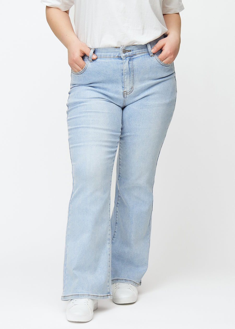Light blue mid-rise bootcut jeans in Waves. Front view on a plus-size model, fitted through the hips and thighs with a gentle flare at the hem.