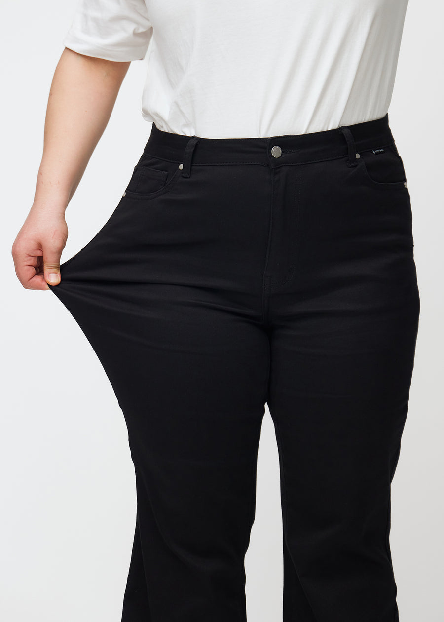 The plus-size model stretches the jeans at the thigh to show the stretch.