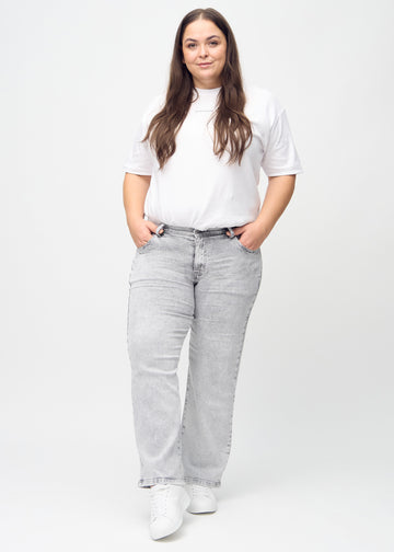 Full image of a plus-size model in light grey denim loose jeans.