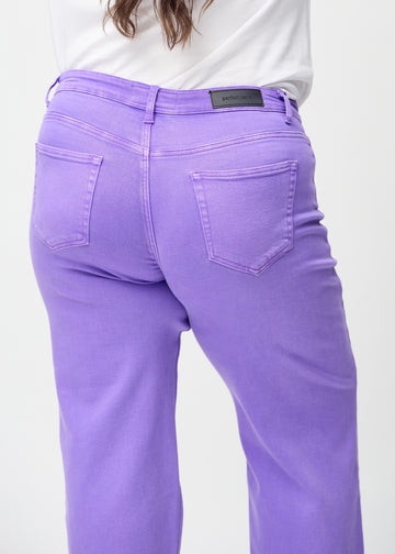 Purple loose jeans seen from the back up close on a plus-size model to show details.
