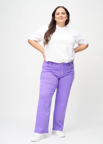 Full image of a plus-size model in purple loose jeans.
