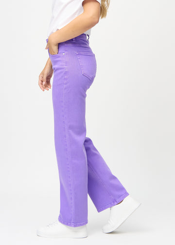 Purple loose jeans seen from the side on a model.
