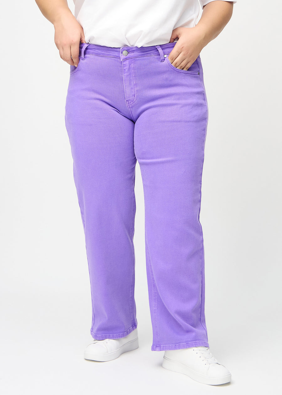 Purple loose jeans, model name Lavenders, which is loose-fitting with plenty of width in the legs on a plus-size model, seen from the front.
