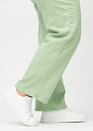 Loose jeans for women in light green, color Mints. Close-up at the ankles on a plus-size model, showing the wide leg openings.