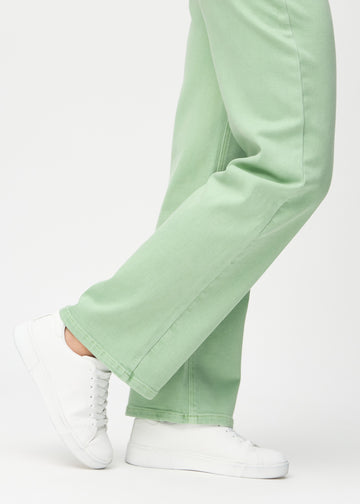 Loose jeans for women in light green, color Mints. Close-up at the ankles on a model, showing the wide leg openings.