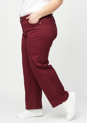 Loose jeans for women in dark red, color Santas. Side view on a plus-size model, showing the loose fit.