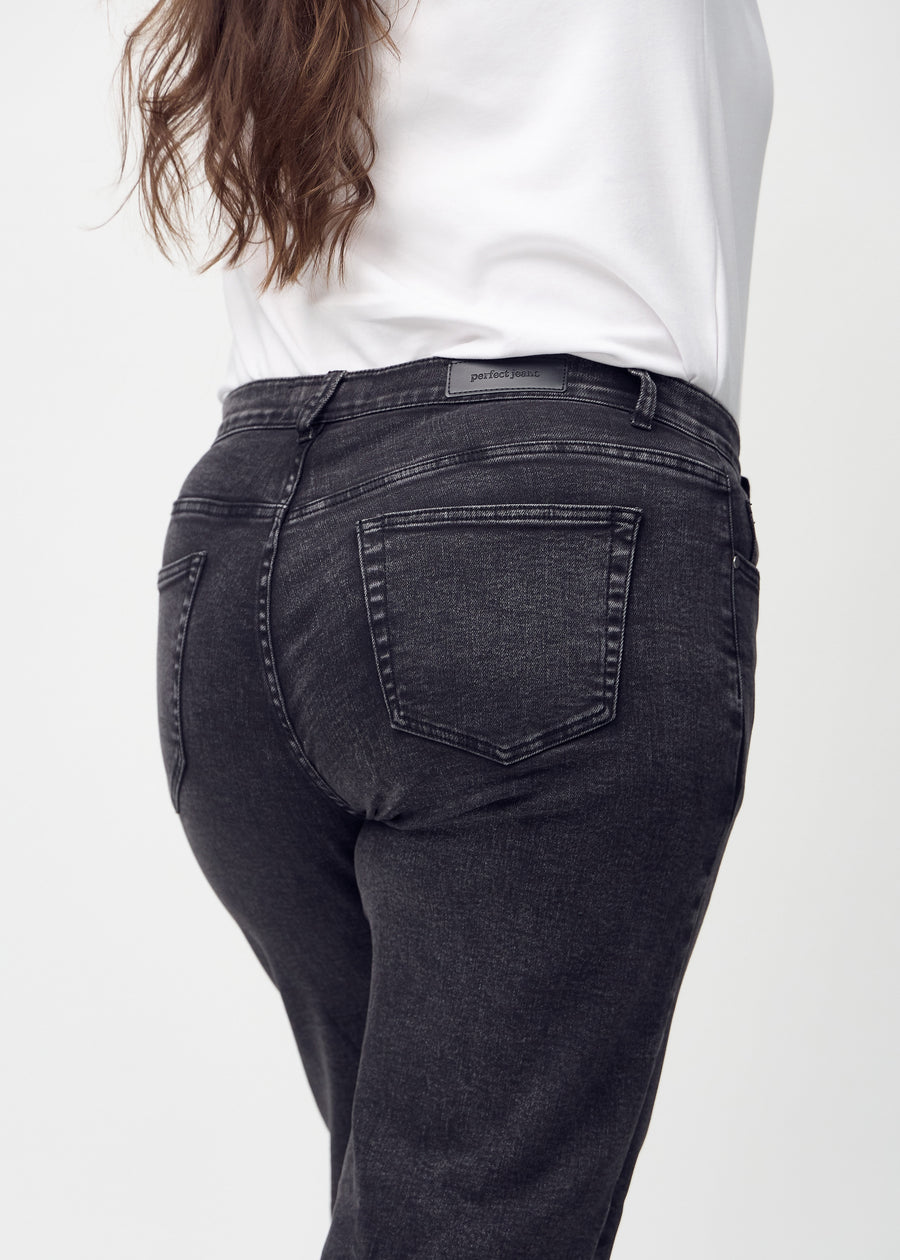 Dark grey denim loose jeans seen from the back close up on a plus-size model to show details.