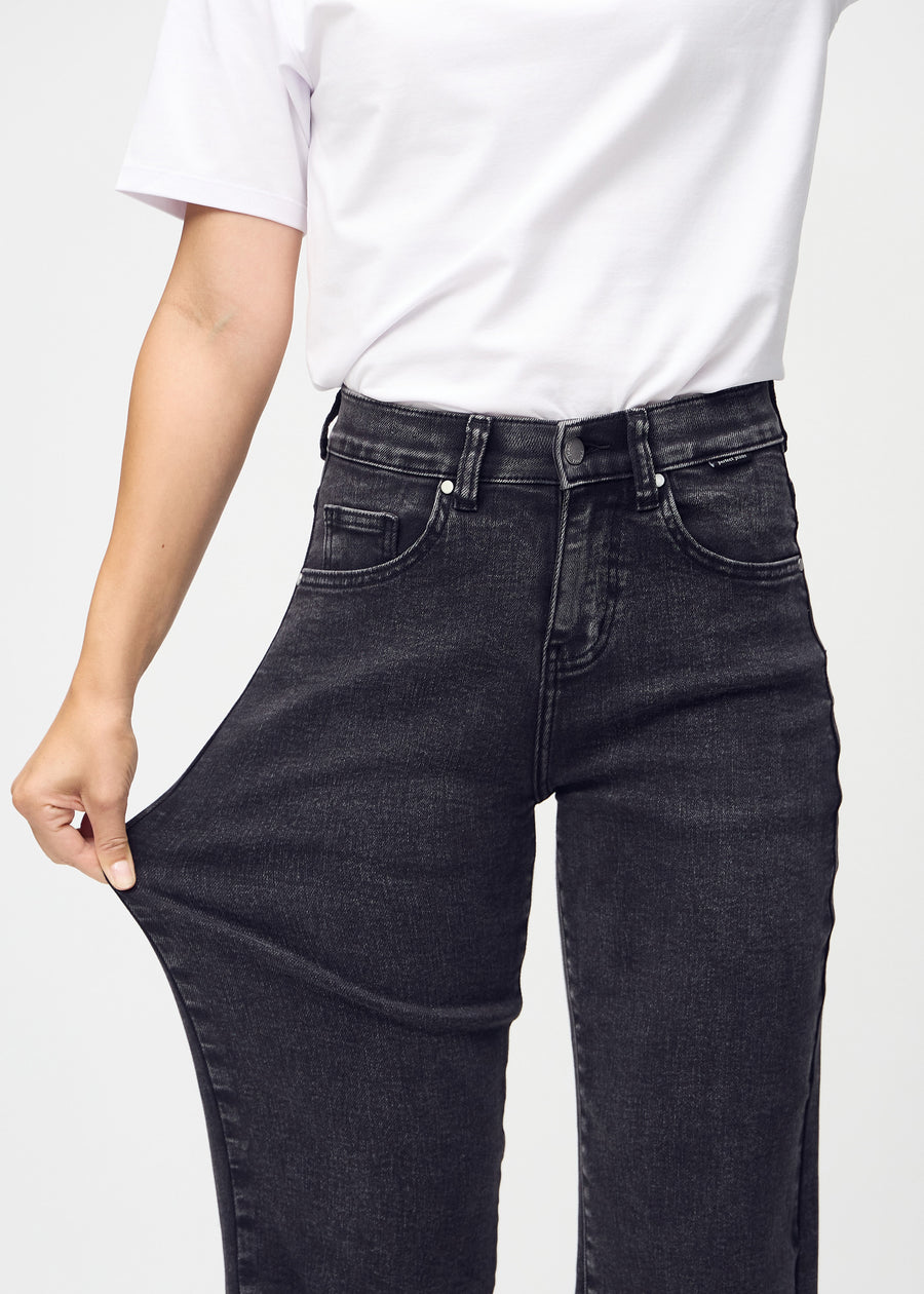 The model stretches the jeans at the thigh to show the stretch.