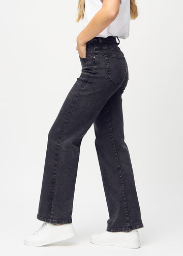 Dark grey denim loose jeans seen from the side on a model.