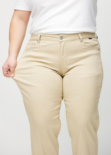 The plus-size model stretches the jeans at the thigh to show the stretch.